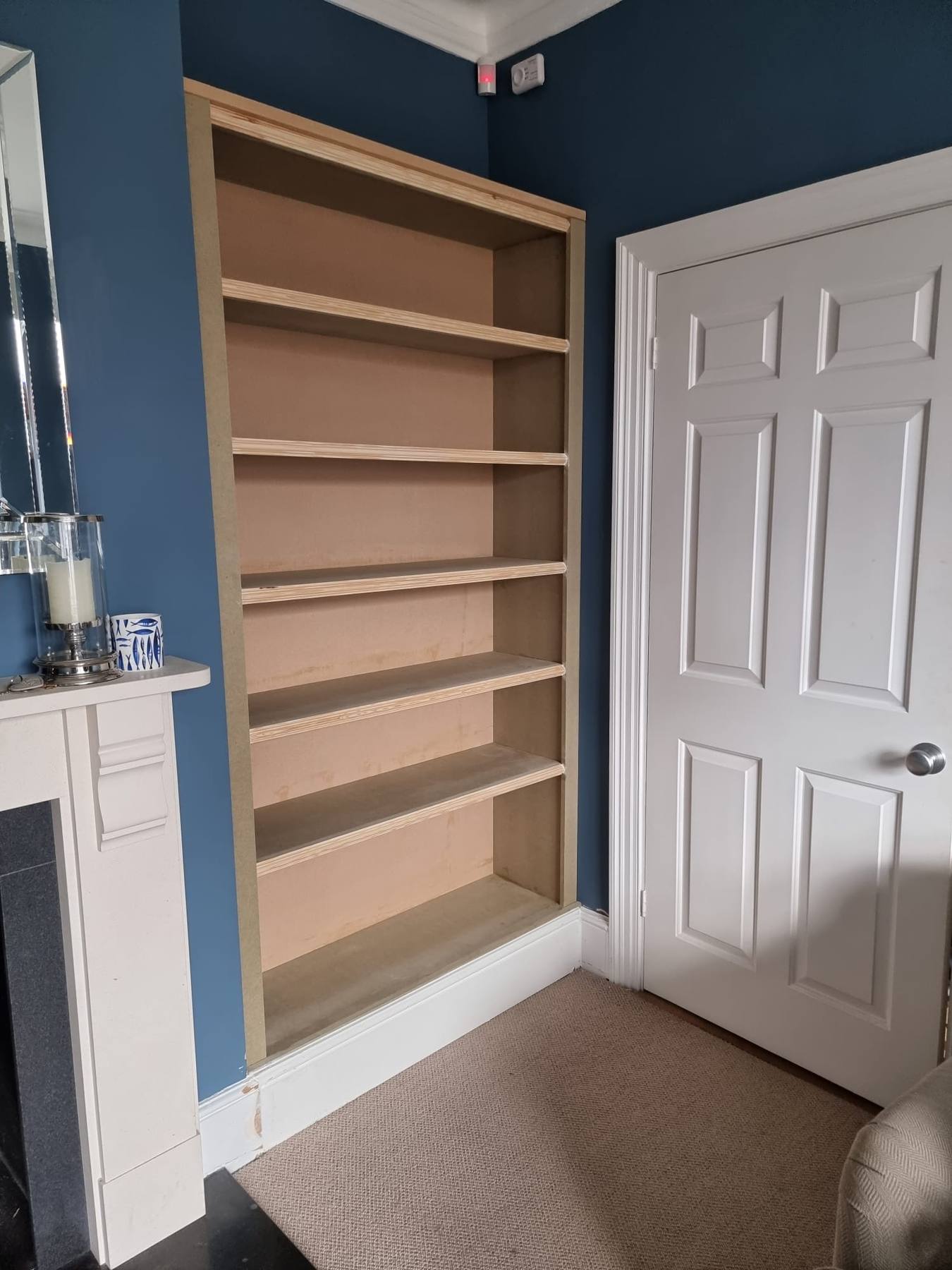 Full-height built-in alcove bookcase beside a chimney breast