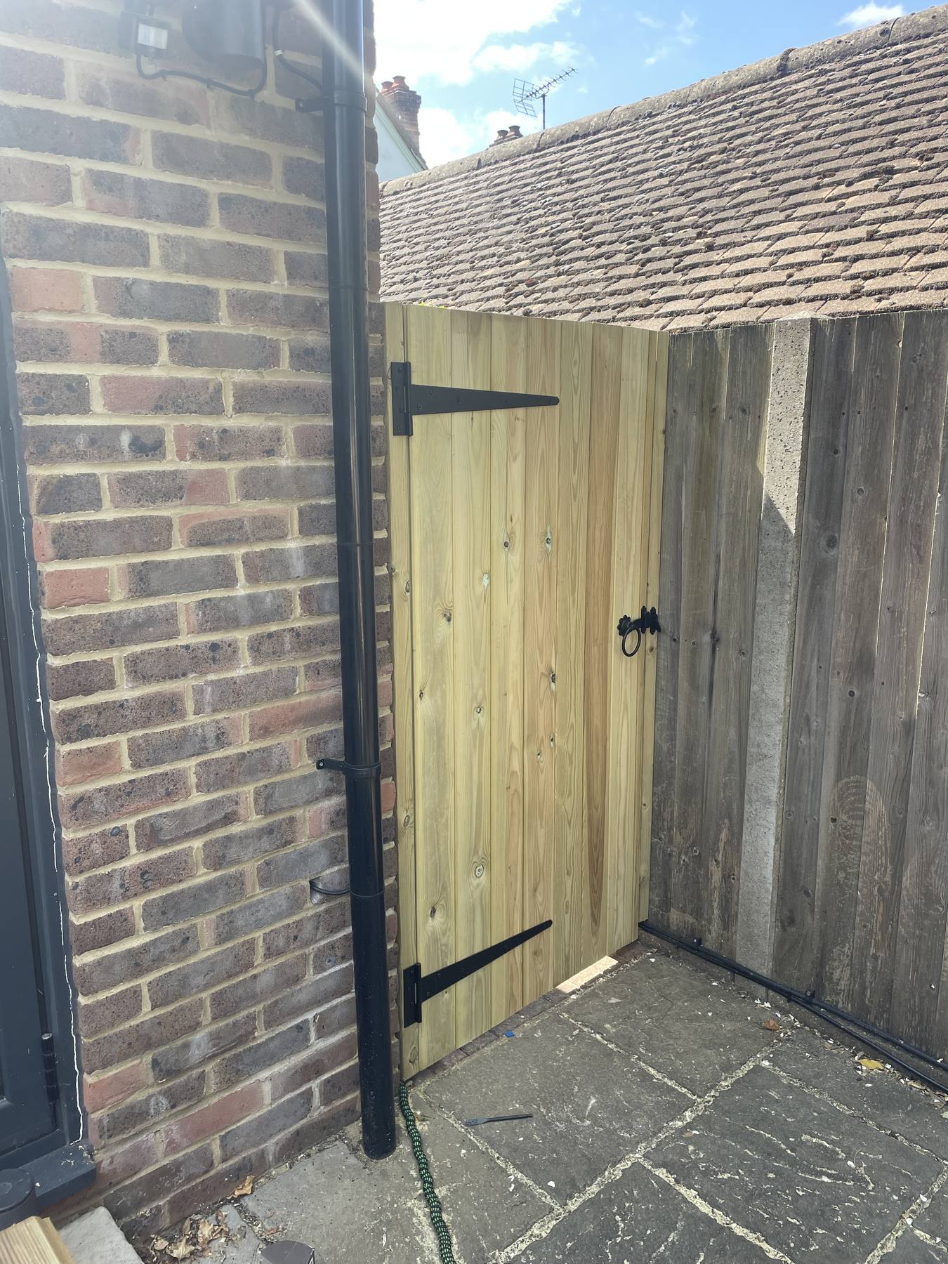 Ledged timber side gate hung on black T-hinges with a ring latch