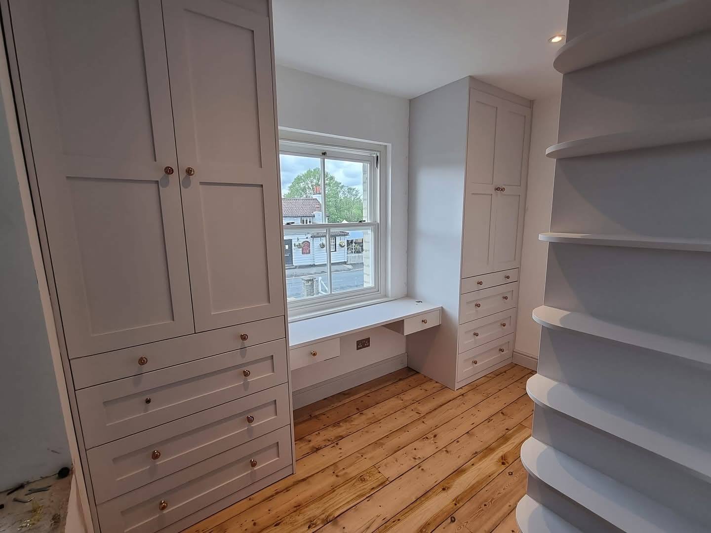 Walk-in wardrobe room with fitted units, drawers and a window seat